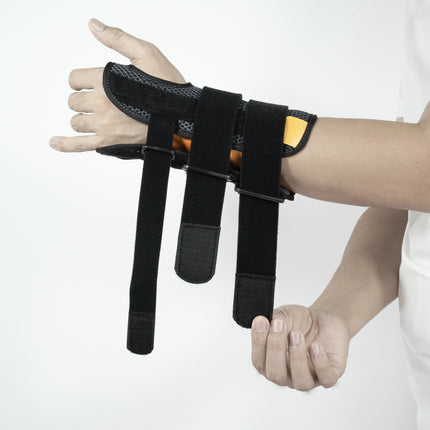 Black wrist support brace on a person's wrist against a white background