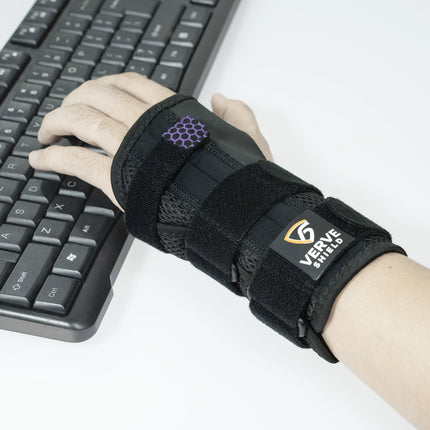 Hand wearing a black wrist support brace with a visible brand logo, using a keyboard.