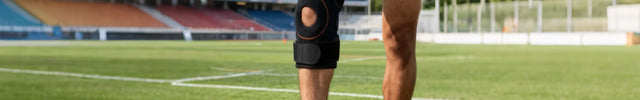 Person on a football field wearing knee brace and preparing to kick a football.