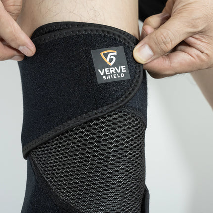 Black knee brace with 'Verve Shield' logo being adjusted on a person's knee.